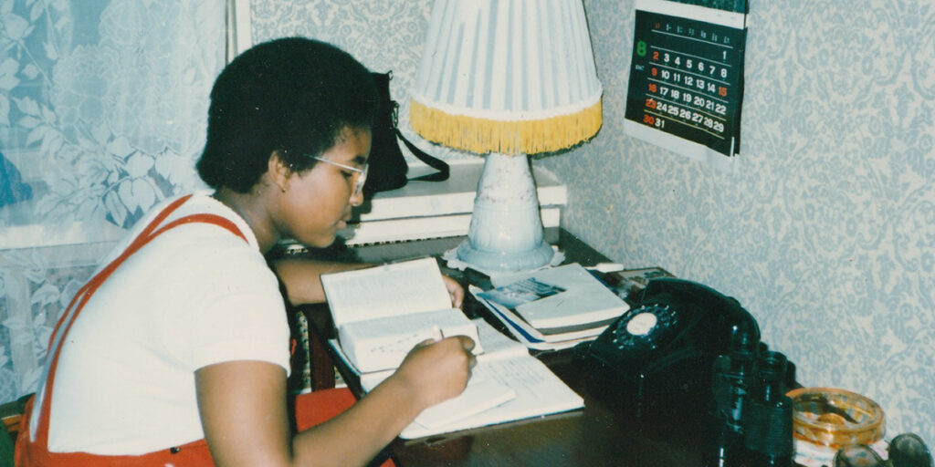 A young Monica writing at her desk in Pyongyang